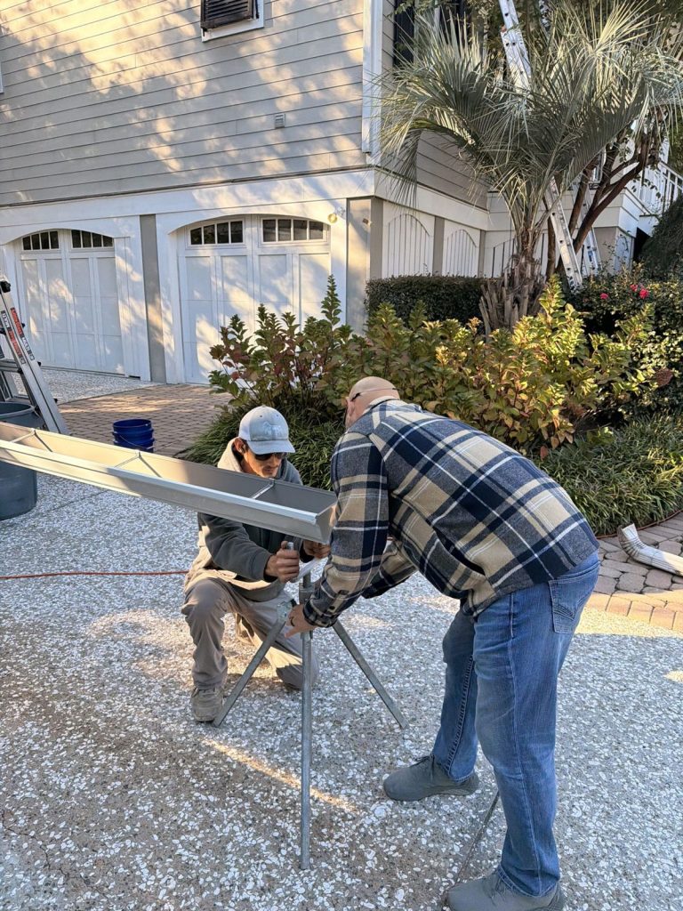 Crew setting up a new seamless gutter run in the driveway